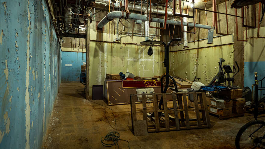 A storage room in the RSL-3 underground bunker, filled with a random assortment of furniture and workout equipment.